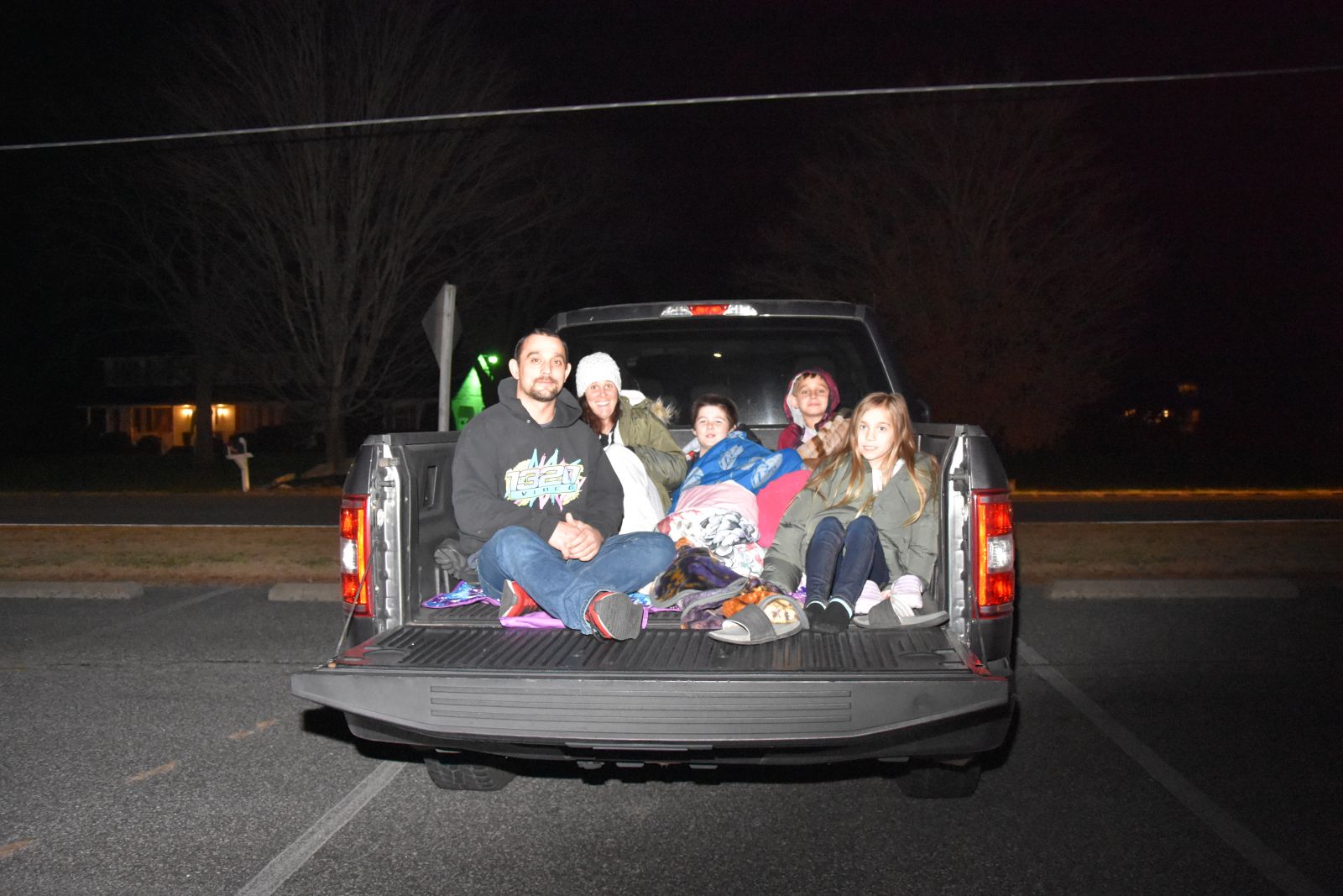 Family sitting in a pickup truck for a drive in movie